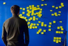 Bootstrapping vs. Fundraising Choosing the Right Path for Your Startup Person standing in front of a wall filled with sticky notes and trying to decide between bootstrappi