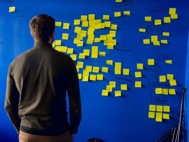 Person standing in front of a wall filled with sticky notes and trying to decide between bootstrappi